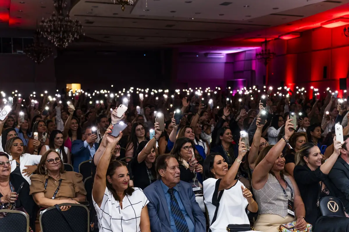 Participantes levantam as lanternas dos celulares no salão do evento