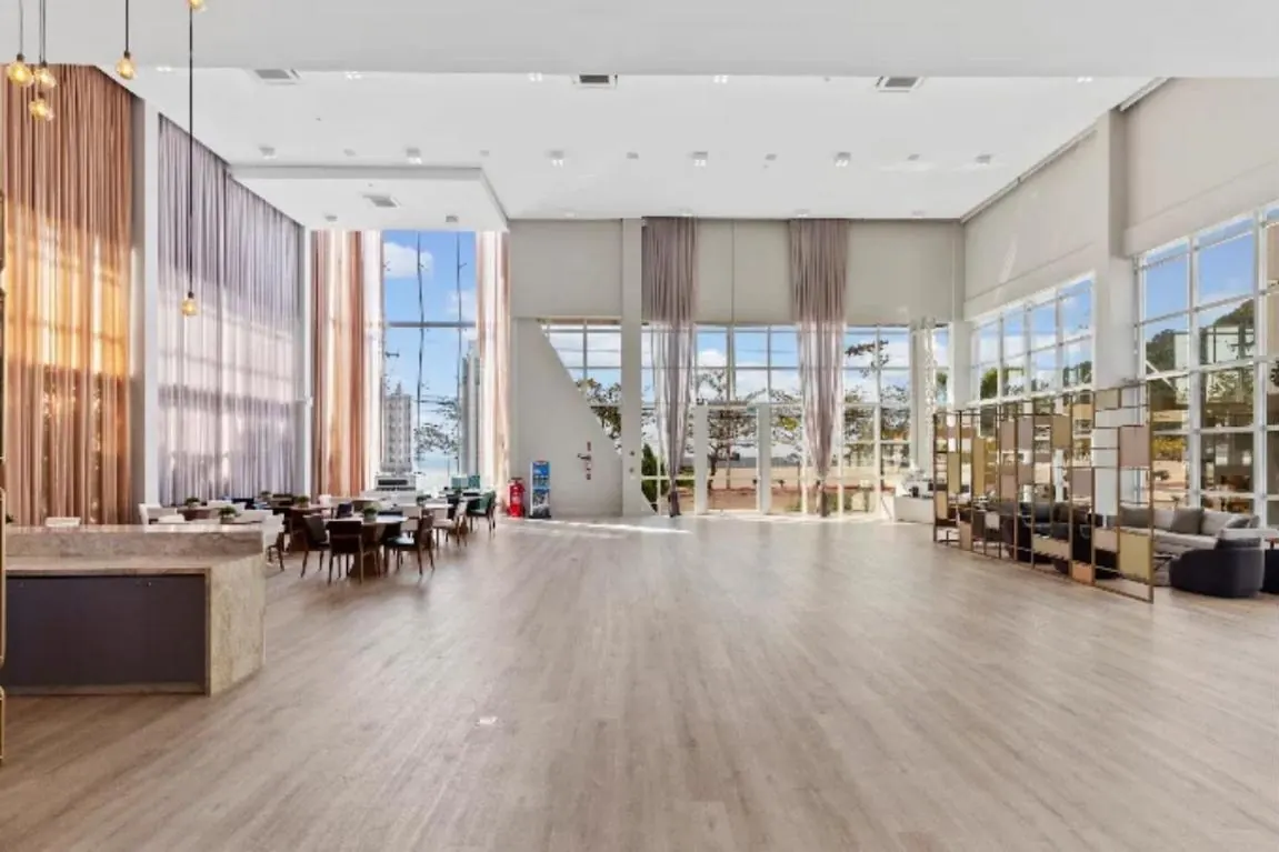 Salão principal do Ocean Place com pé-direito alto e janelas amplas